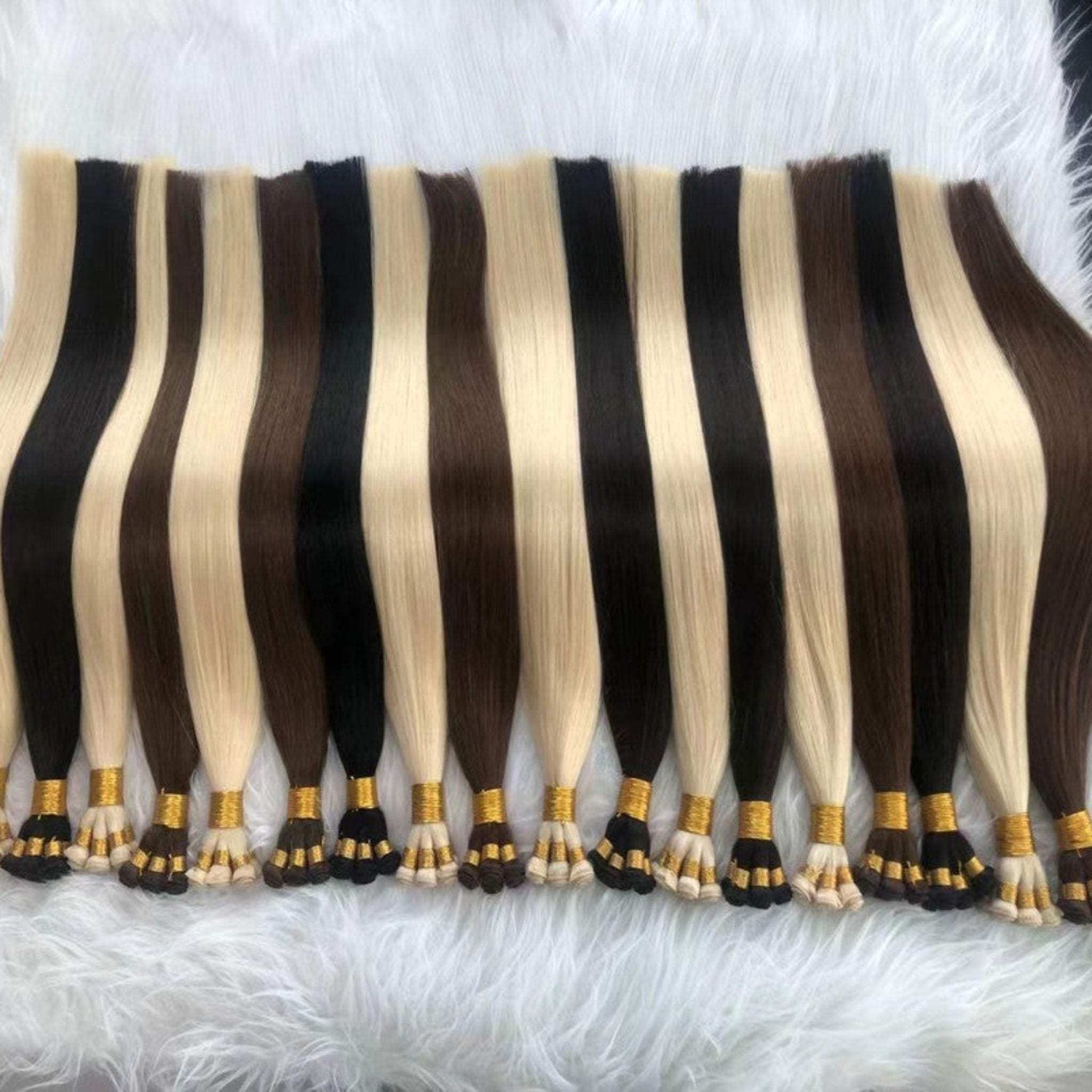 Hand tied weft extensions in various colors, 24-inch length, on a white fur background.